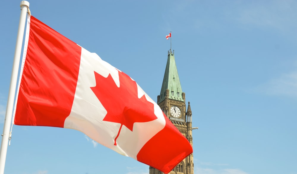 A Canadian flag in front of the parliament building