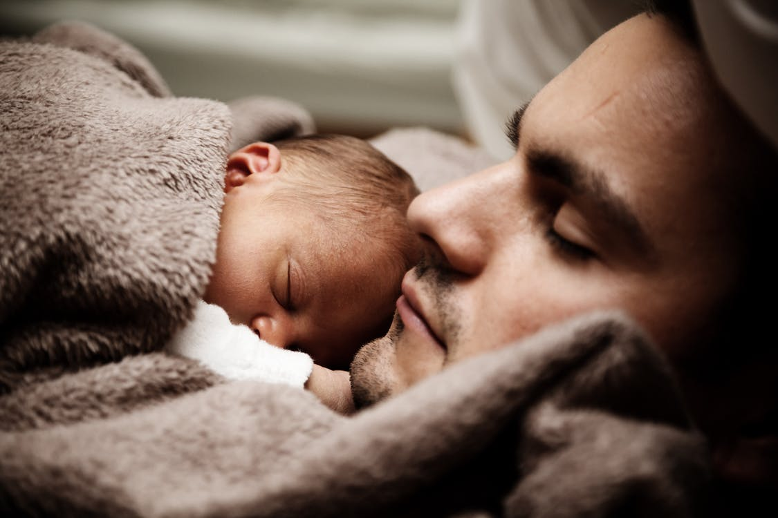 A father sleeping with his young baby